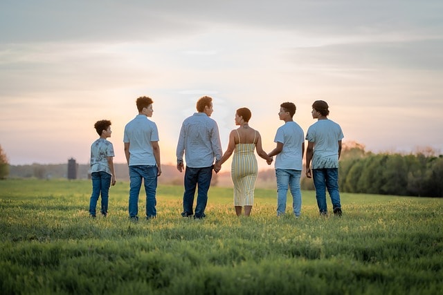 Family standing on grass at sunset