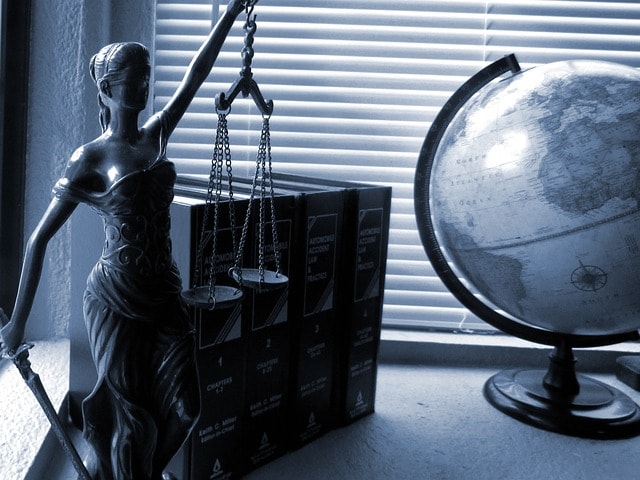 Lady Justice with scales and a sword beside books and a globe