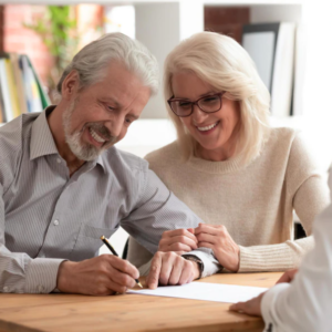 Mature age couple happily signing a document together